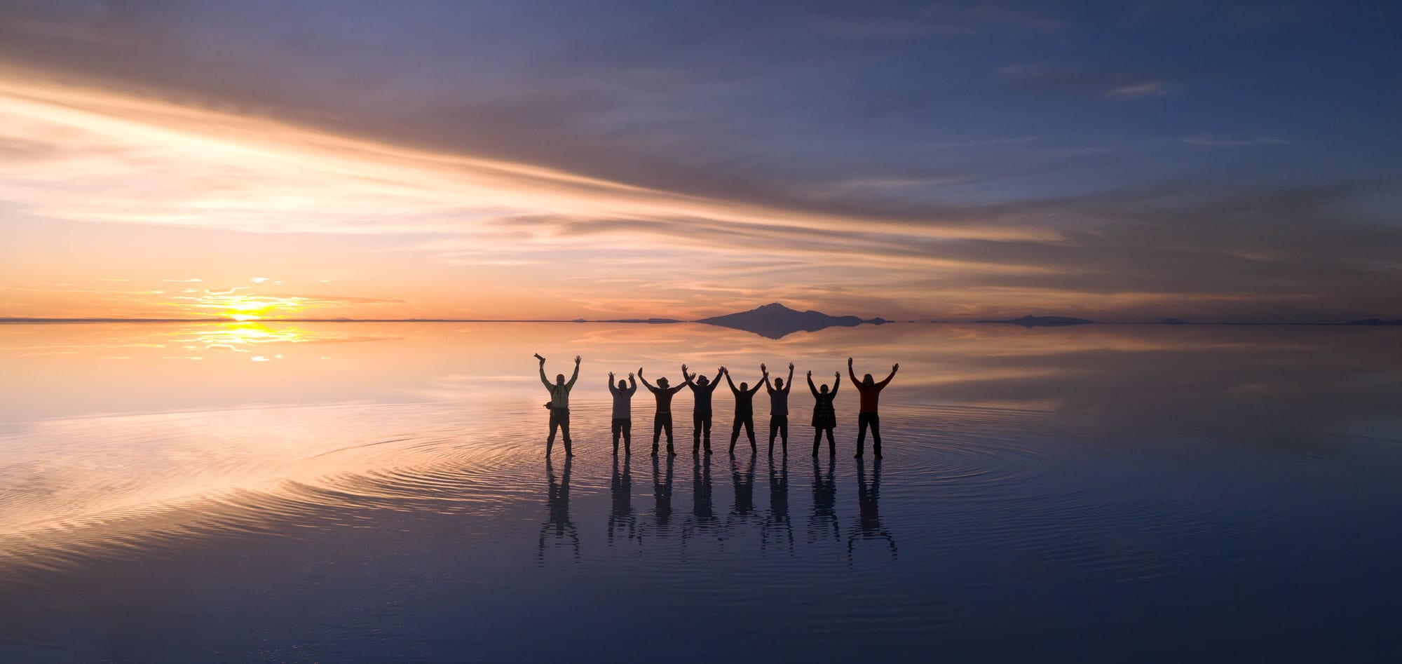 Un grupo de viajeros en el salar de Uyuni al atardecer.