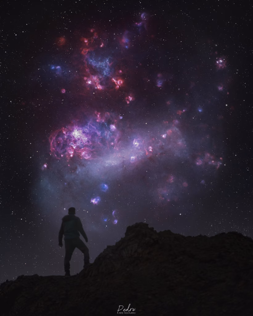 Una persona de pie sobre unas rocas bajo un cielo estrellado con nebulosas.